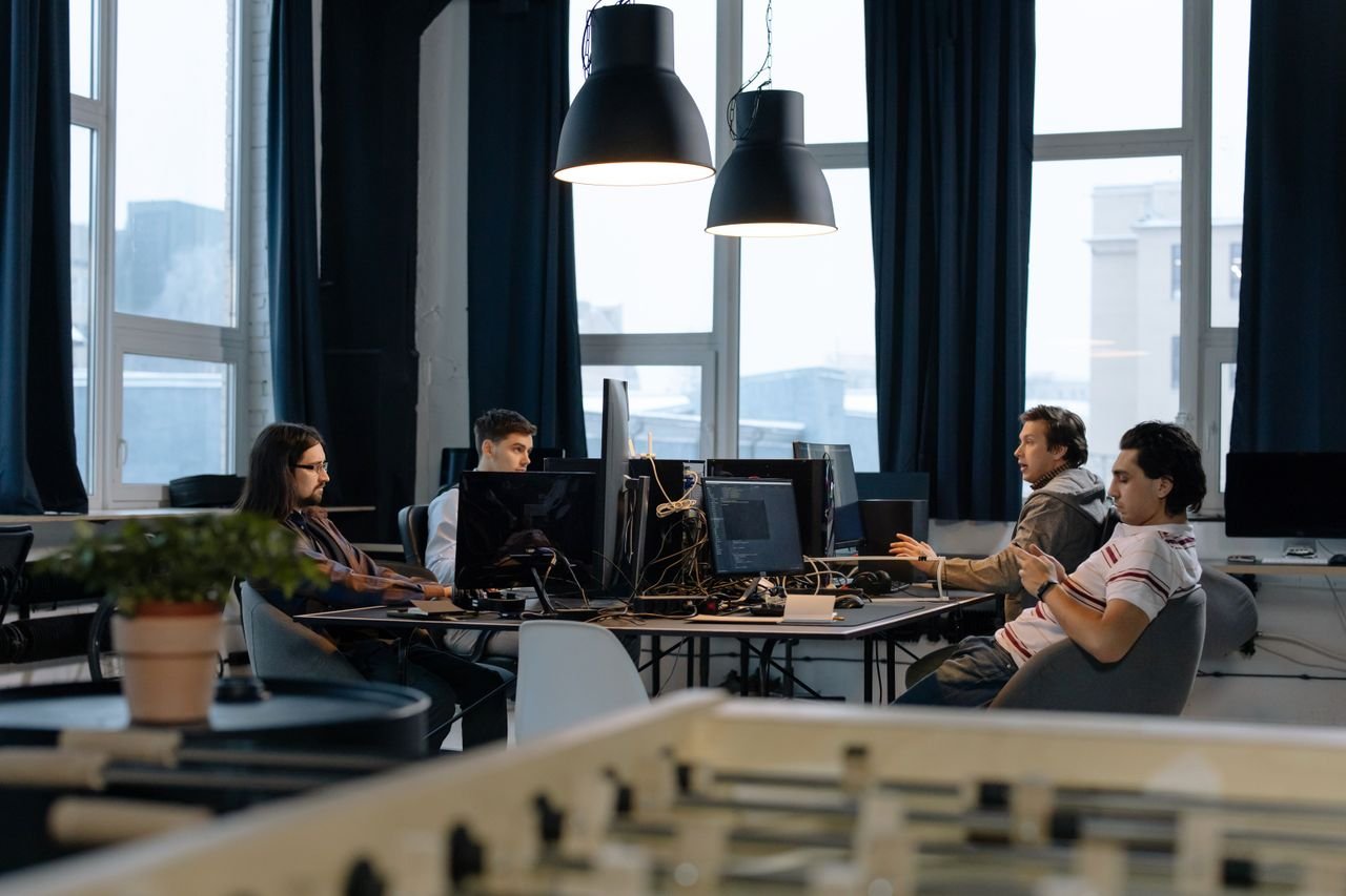 Workers collaborate in a modern office with computers, showcasing teamwork in technology development.