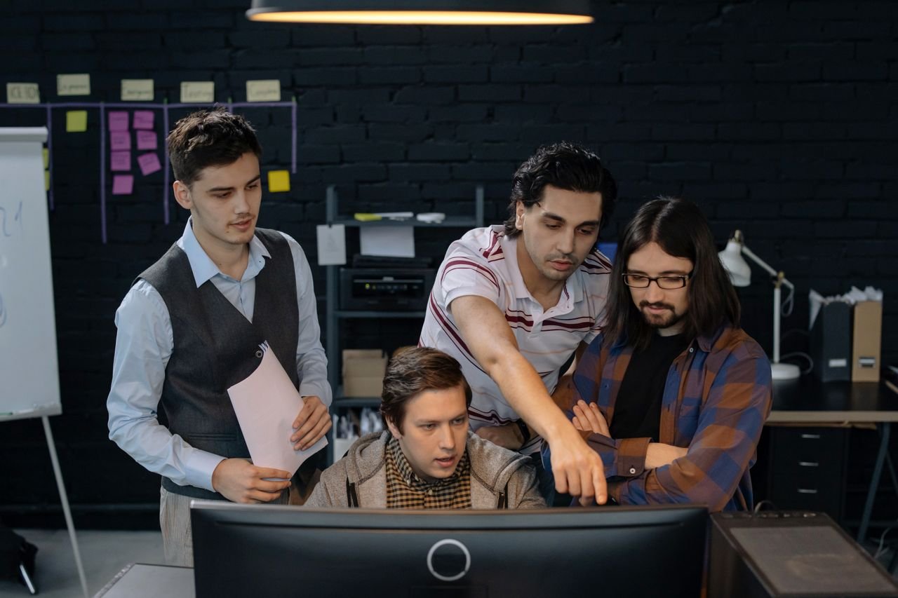 our-stories Group of professionals discussing a project at a computer in a modern office environment.
